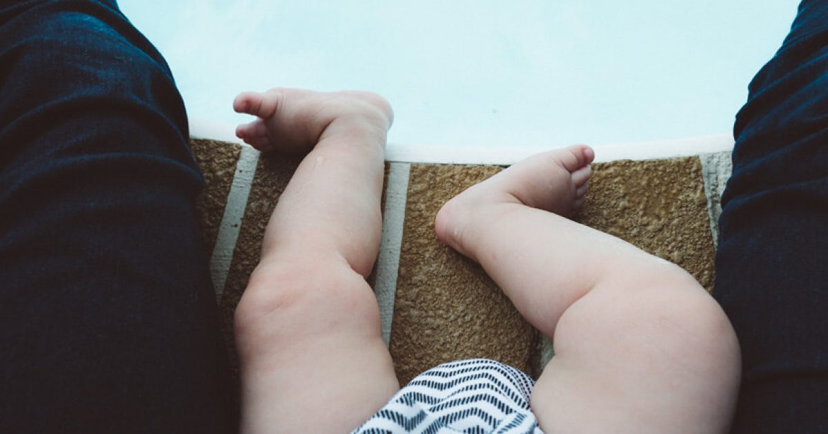 baby’s legs at edge of pool wearing white and gray stripes