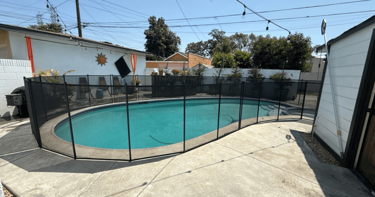 swimming pool with black mesh pool fence surrounding it
