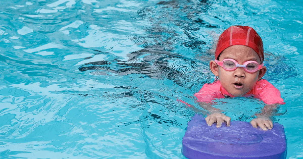 child learning how to swim with swimming equipment