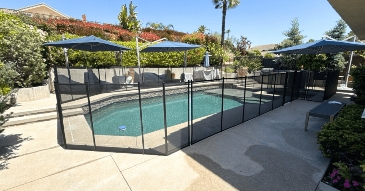 black mesh pool fence installed around a swimming pool with three blue umbrellas