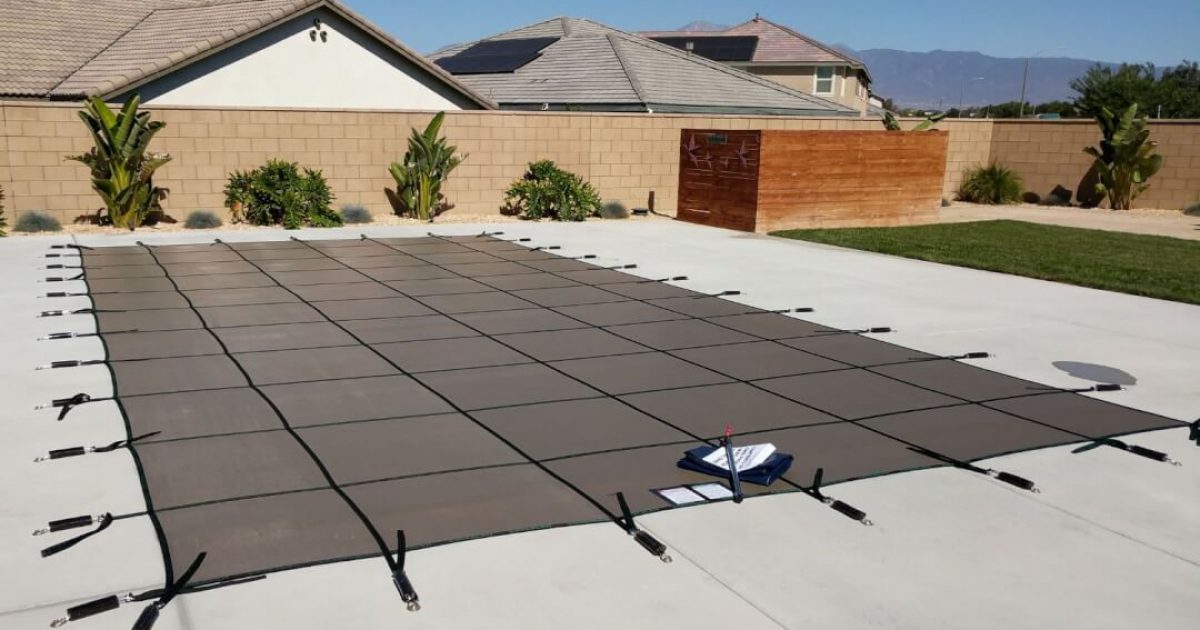 black mesh pool safety cover installed on a rectangular swimming pool