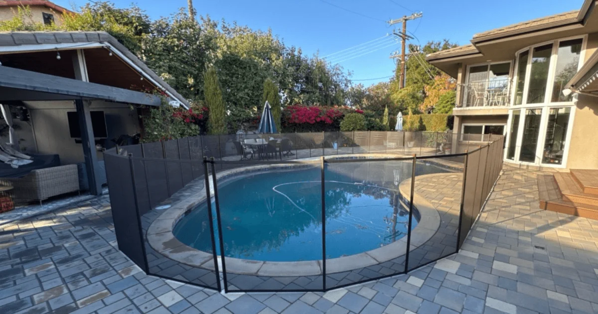 brown mesh removable pool fence installed on pavers in a backyard