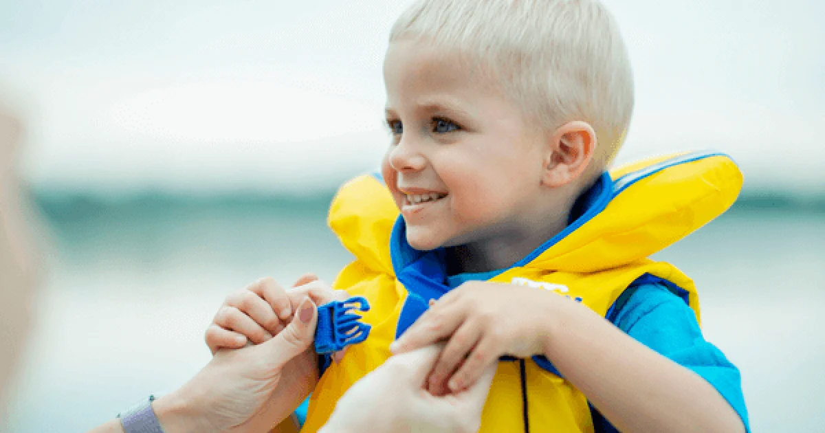 Child being fastened into a life vest