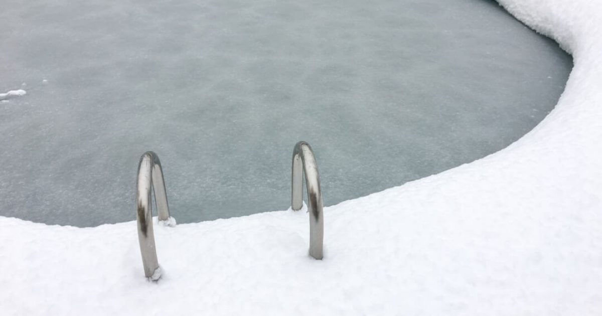 snow surrounding a frozen swimming pool