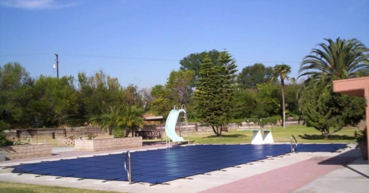 blue mesh winter pool cover secured on a backyard swimming pool