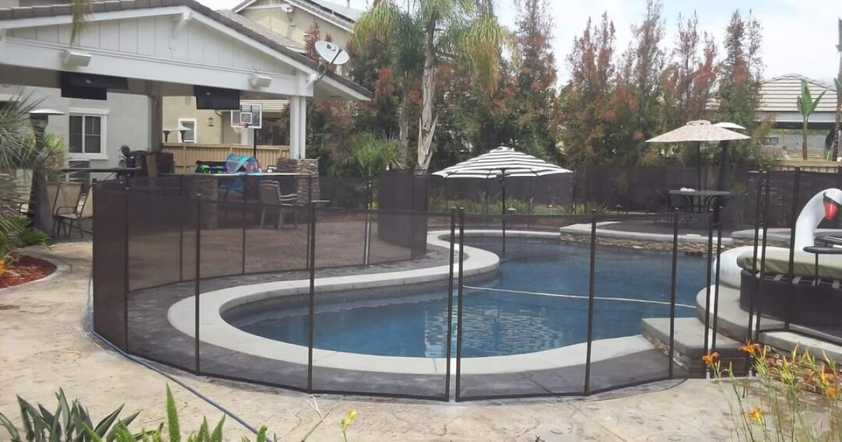 Black mesh removable pool fence installed around a residential swimming pool