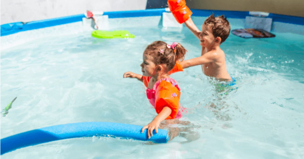 boy and girl splashing in pool with pool toys