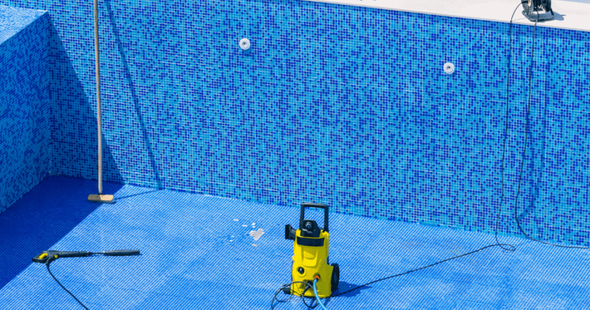 Empty swimming pool with cleaning tools sitting at the bottom