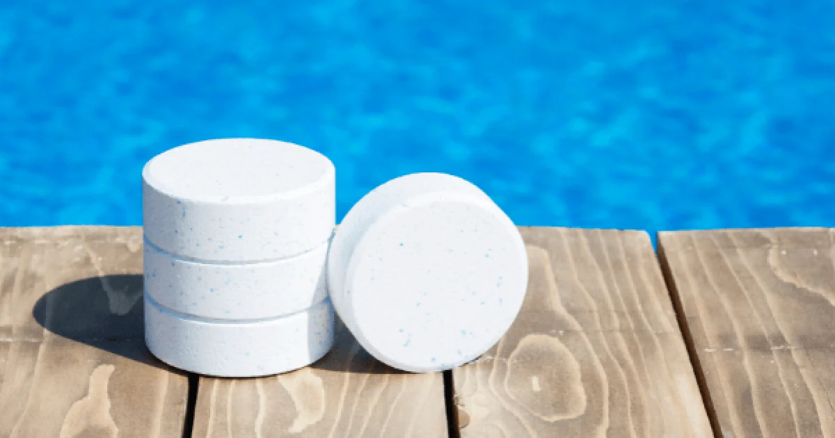 chlorine pool tablets stacked next to a swimming pool