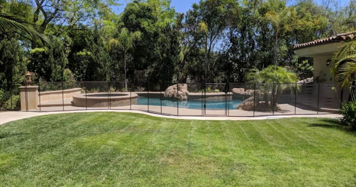 Beautiful backyard swimming area with a black mesh pool fence installed
