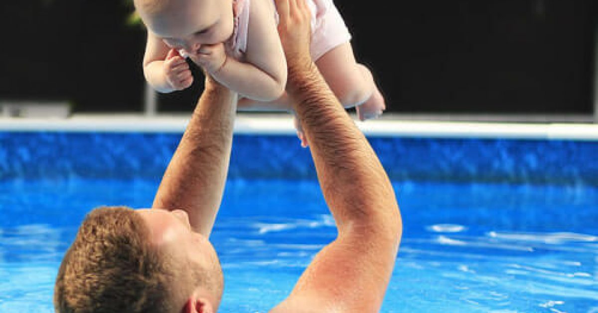 man-holding-baby-above-him-swimming-pool