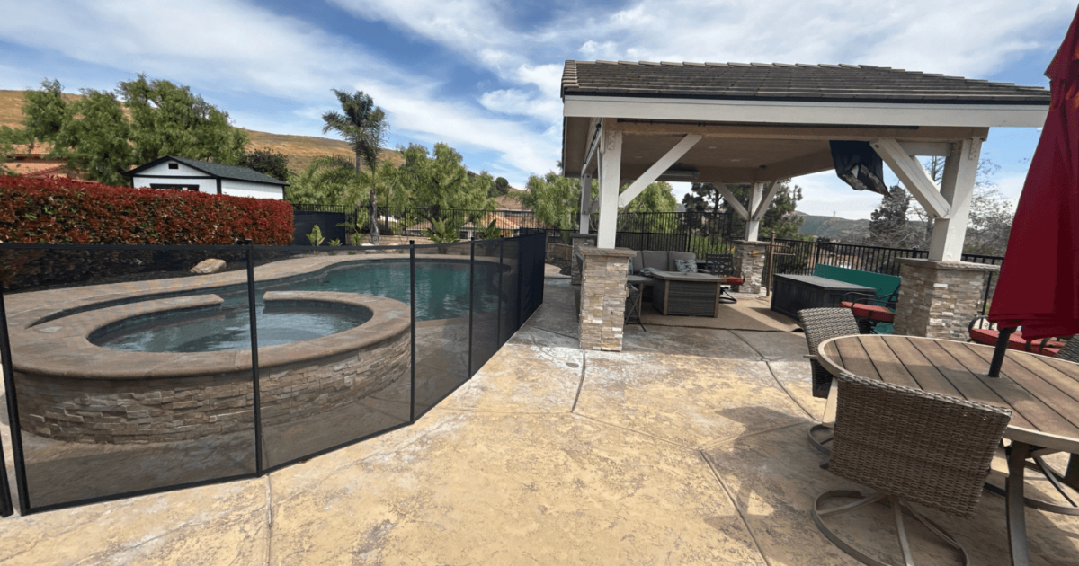 backyard with lounge area and swimming pool enclosed with a black mesh pool fence