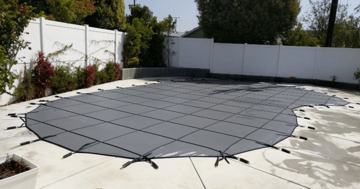 Black mesh swimming pool safety cover installed on a swimming pool