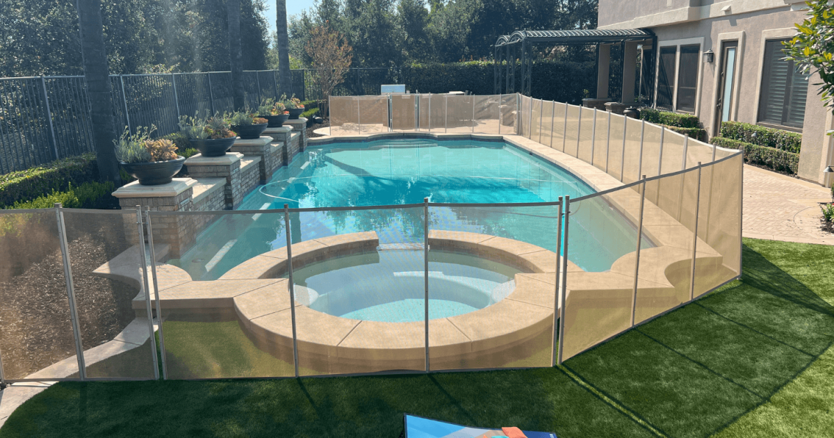 tan mesh pool fence installed around a swimming pool and hot tub