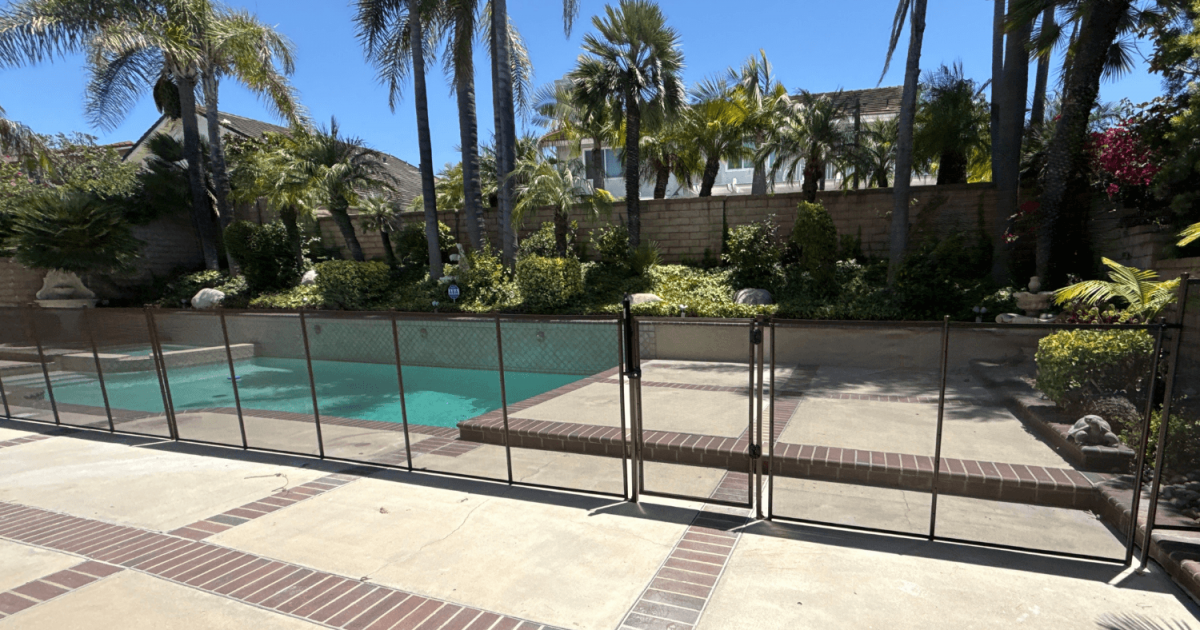 brown mesh pool safety fence bordering a backyard swimming pool