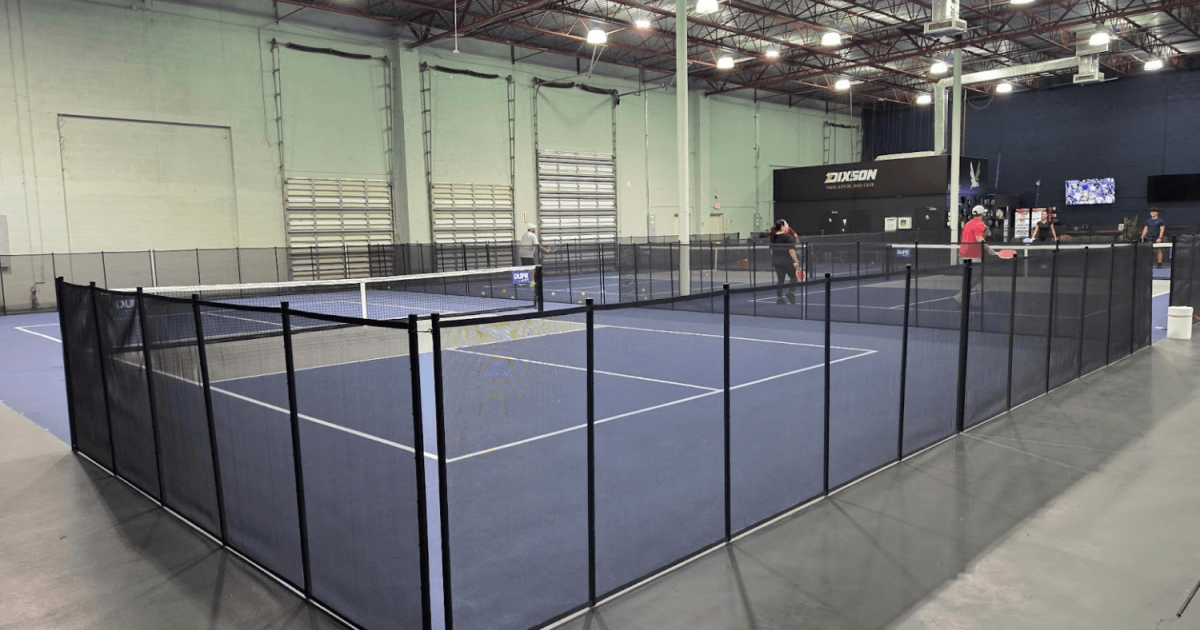 Black mesh removable pool fencing installed surrounding an indoor pickleball court