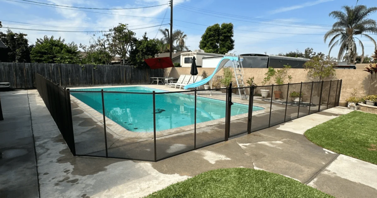 removable mesh pool fence installed around a backyard swimming pool
