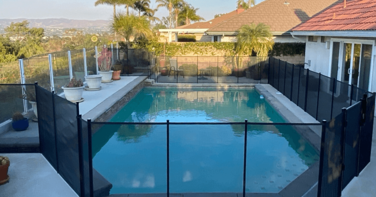 black mesh removable pool fence installed around a hillside backyard pool
