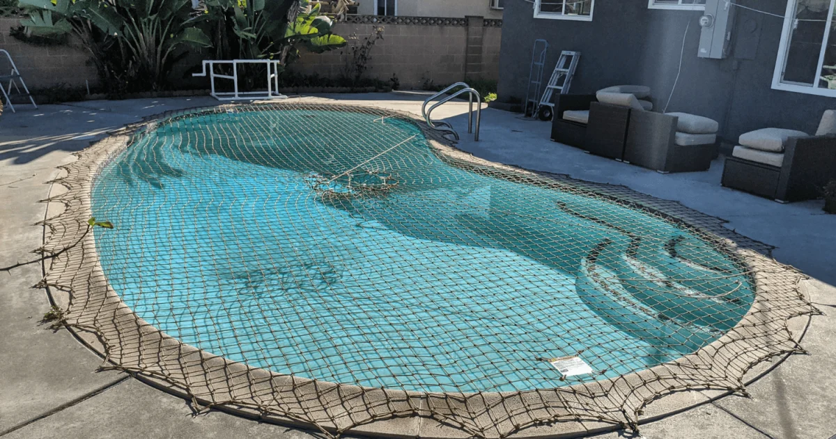 tan pool safety net installed over a backyard swimming pool