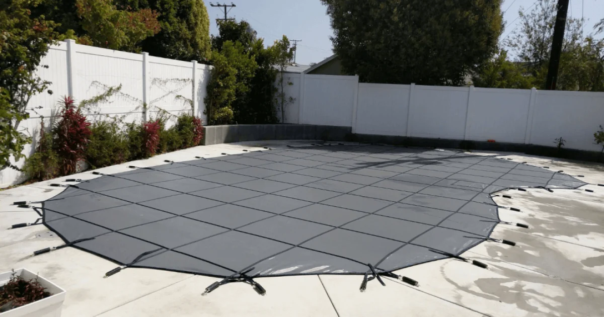 black winter pool cover installed over an irregular swimming pool