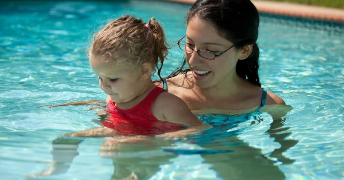 young woman in pool holding infant